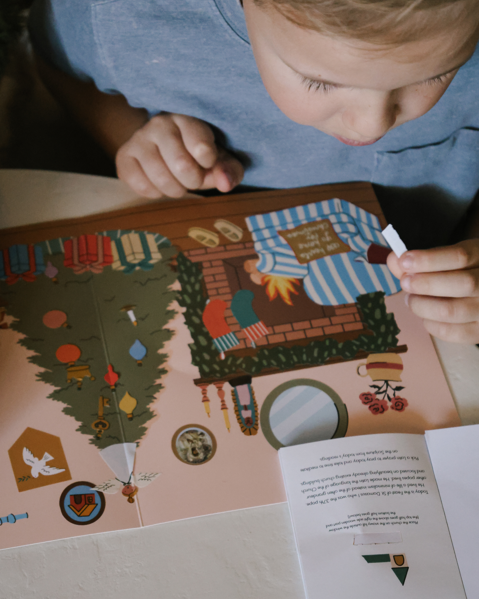 Liturgical Advent Calendar with illustrated scene and 26 sticker sheets, teaching children about Advent, feast days, and Christmas traditions. Suitable for ages 4+.