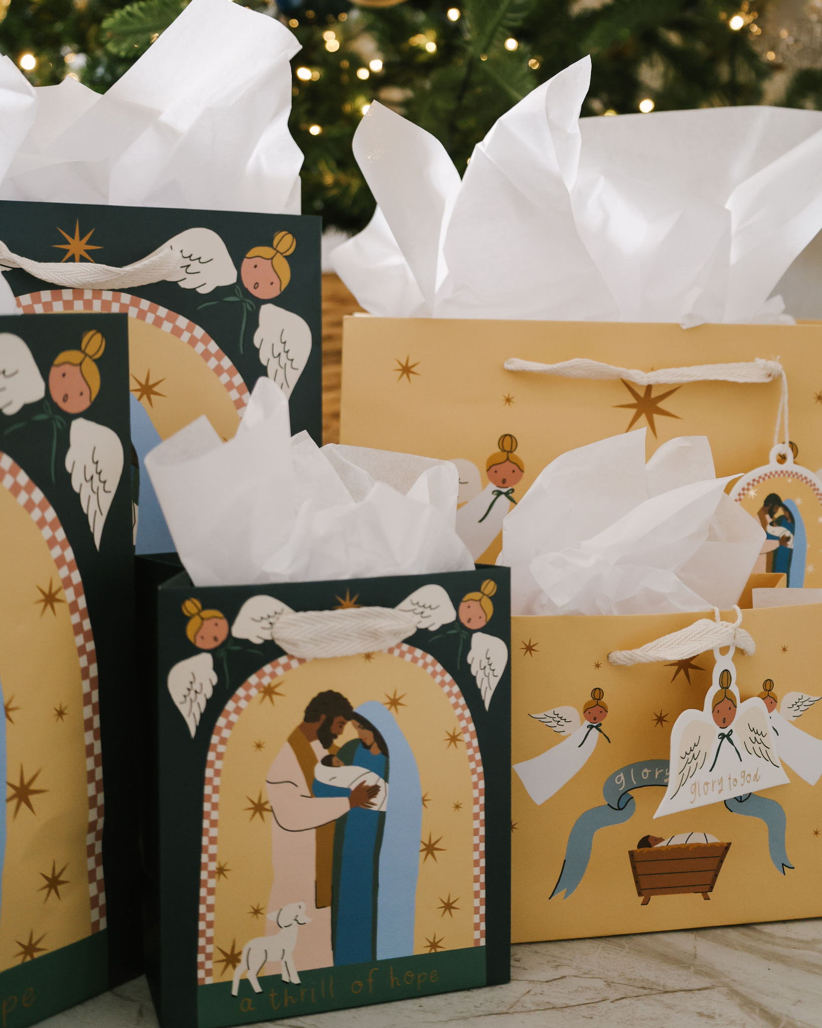 Glory to God Christmas gift bag set with baby Jesus in the manger, angels, and starry sky design. Includes 5 bags in 3 sizes with cotton ribbon handles and matching gift tags.