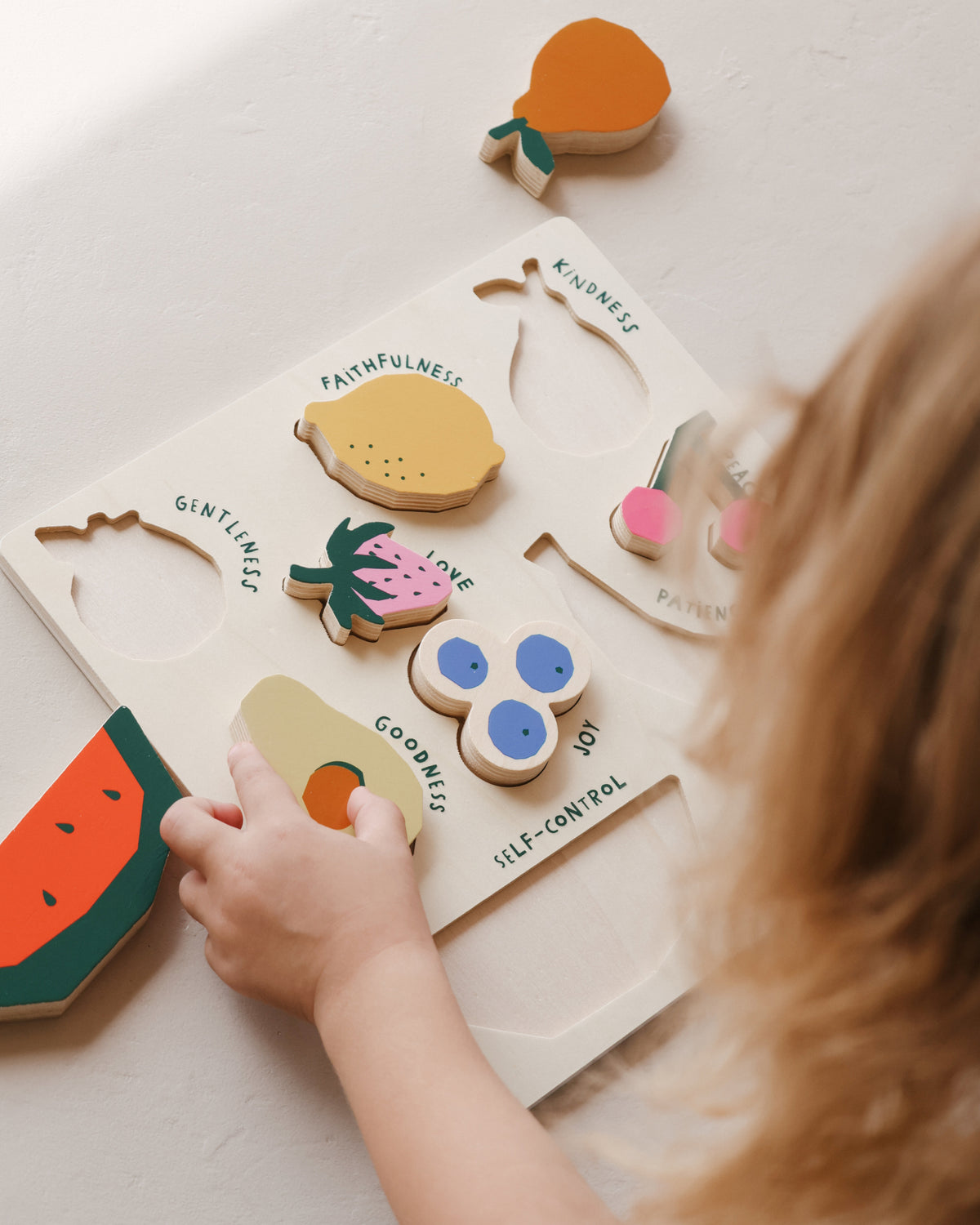 Toddler playing with the Fruit of the Spirit chunky wooden puzzle