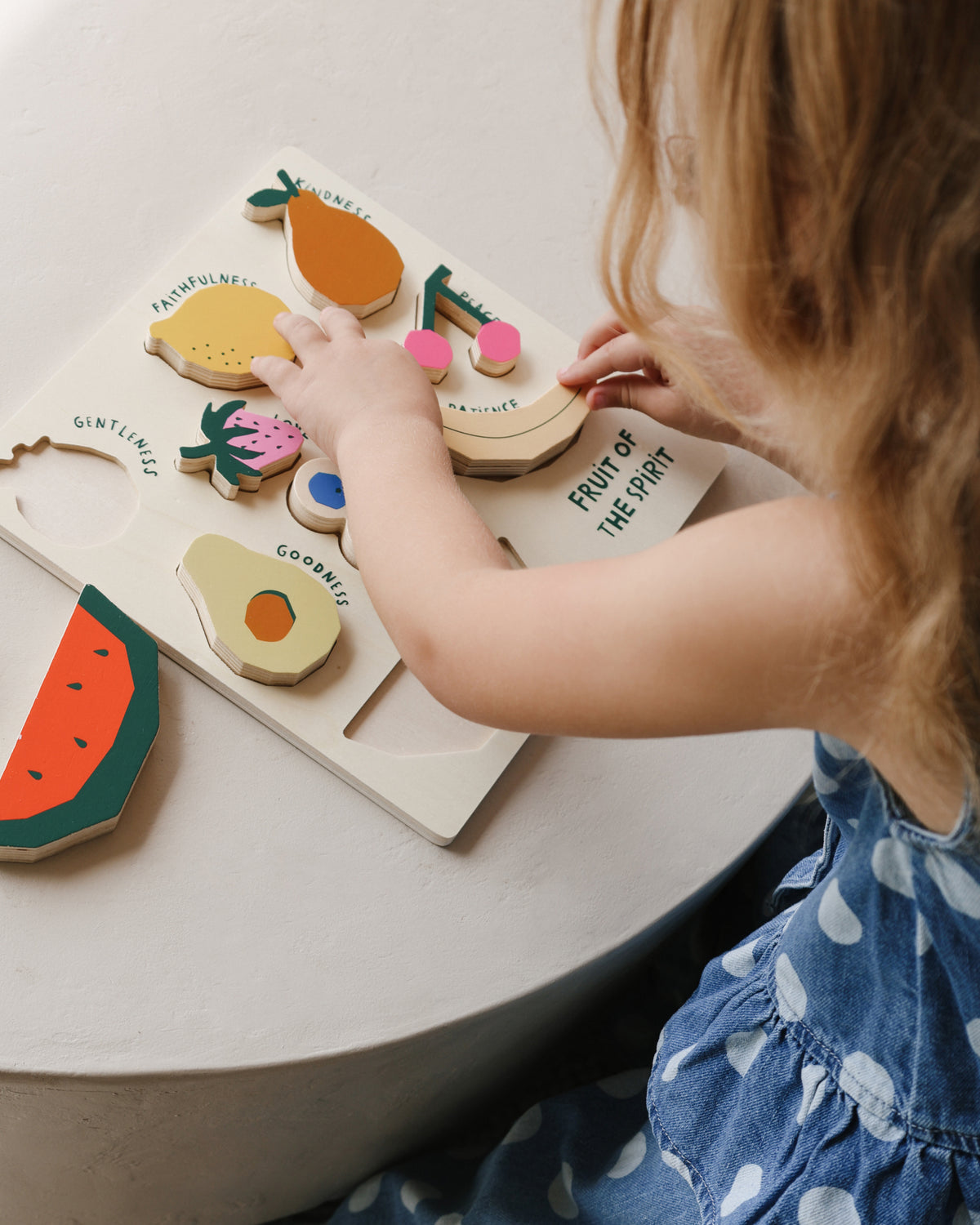 Little girl completing the Fruit of the Spirit wooden puzzle