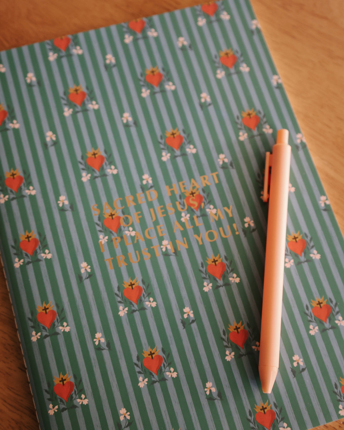 Sacred Heart of Jesus journal with a pen, green striped cover with red Sacred Hearts