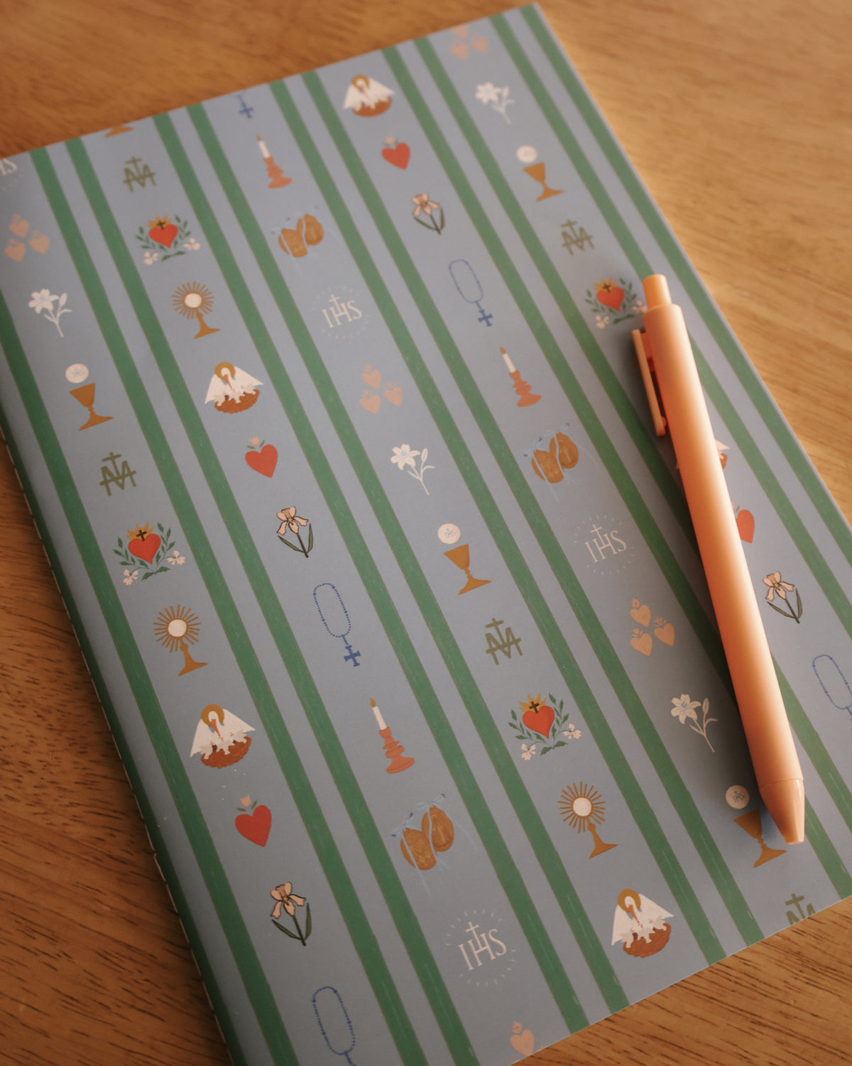 Catholic Devotions Journal with a pen, blue and green striped cover with devotional symbols