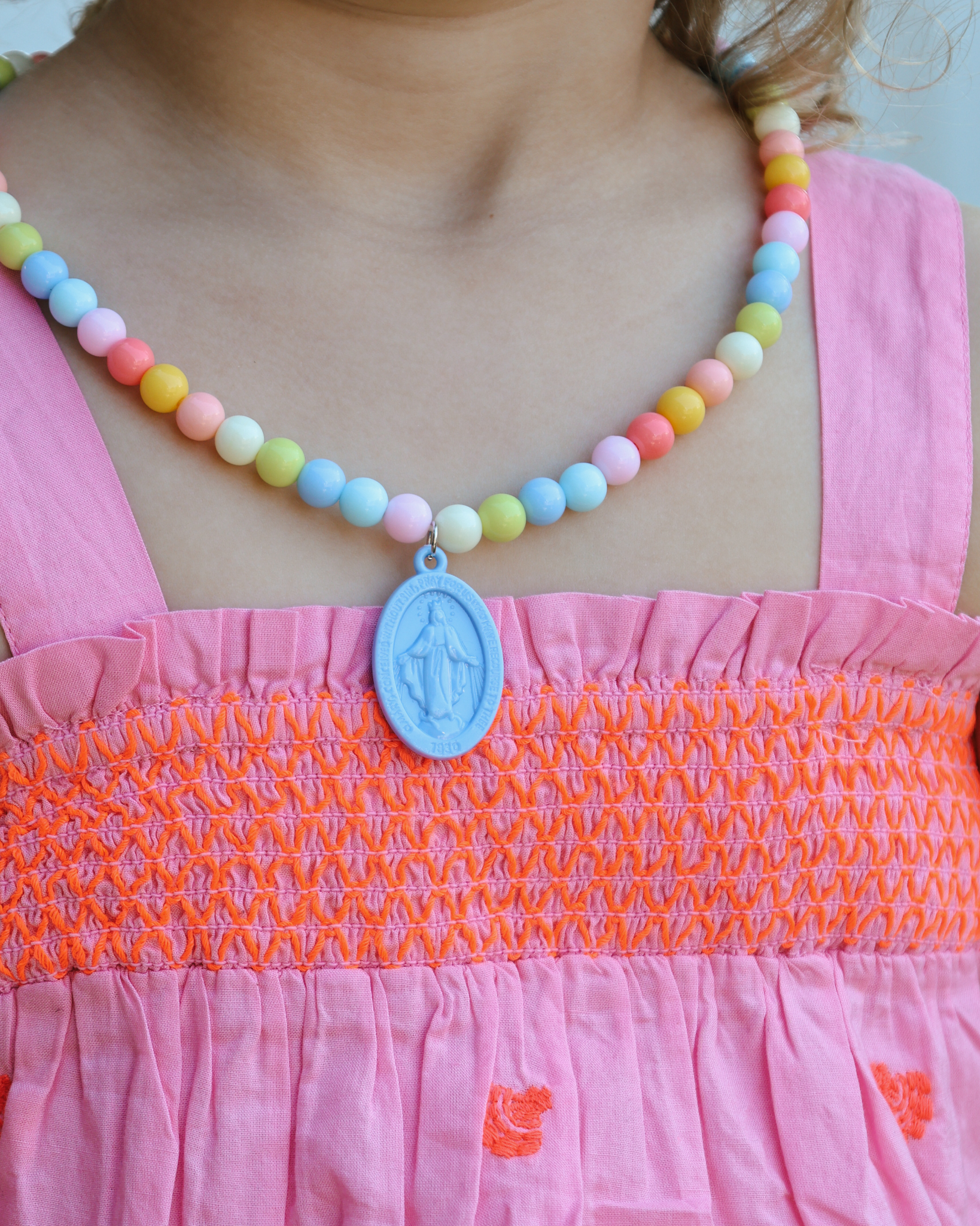 Children’s Miraculous Medal necklace with soft blue medal and colorful plastic beads on elastic strand. Christian kids’ jewelry for Marian devotion, First Communion, or faith-based gifts, reminding children of Mary’s protection and intercession.