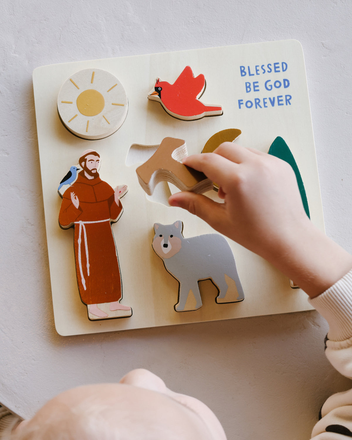 Toddler playing with the St. Francis Wooden Puzzle, a Catholic baptism and birthday gift