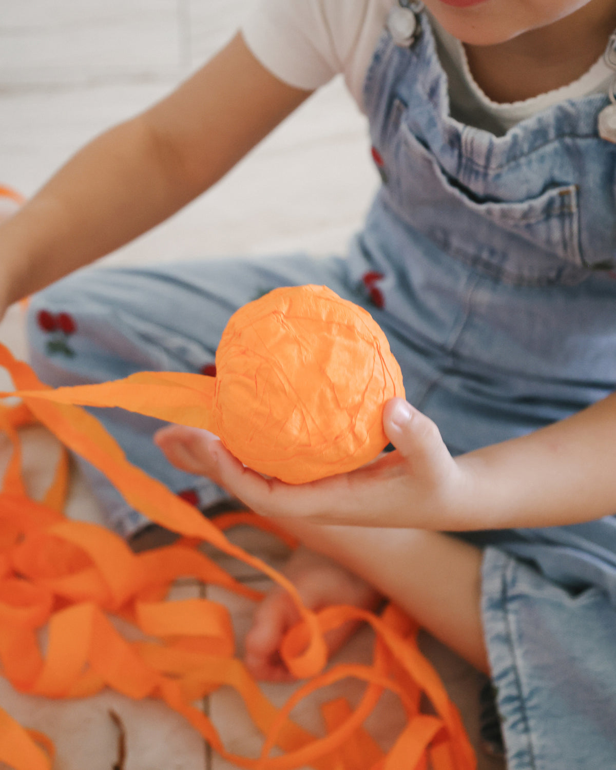 Half unwrapped St. Nicholas Orange Surprise Ball surrounded by crepe paper streamers