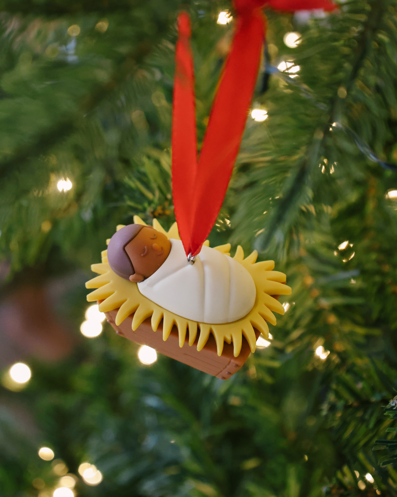 Baby Jesus Christmas ornament made of shatterproof resin with red ribbon, ideal holiday gift for children.