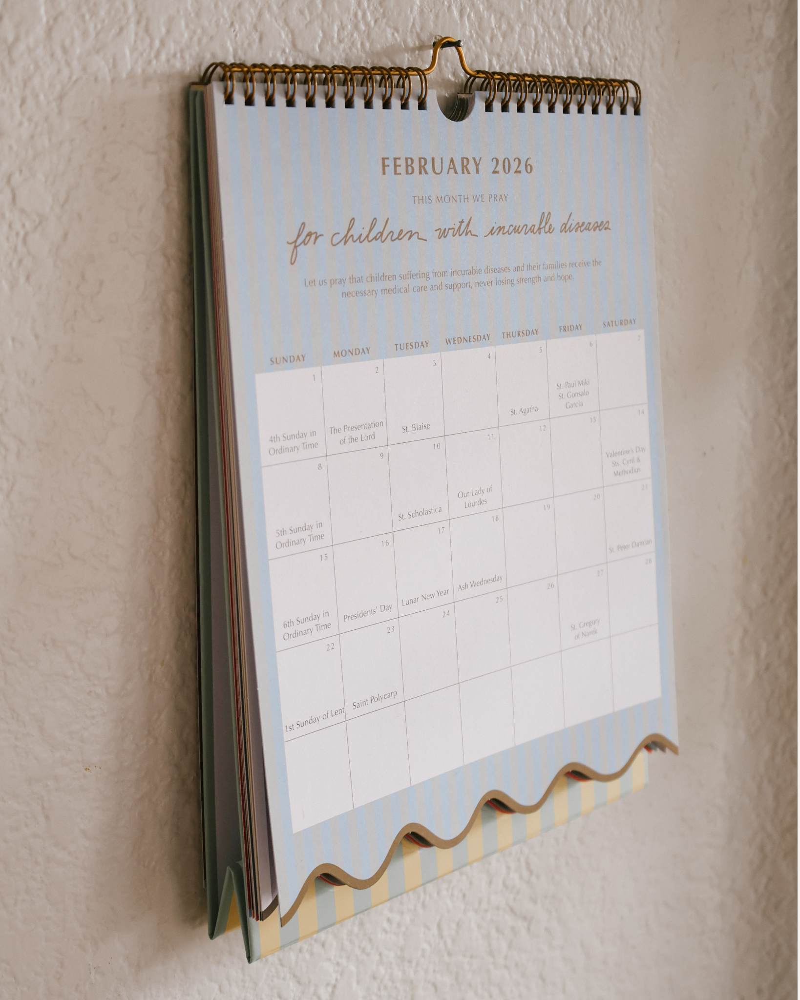 2026 Catholic liturgical calendar with colorful stripes, monthly prayers by Pope Francis, and all feast days and US holidays. Available as wall calendar or wall + desk stand combo.