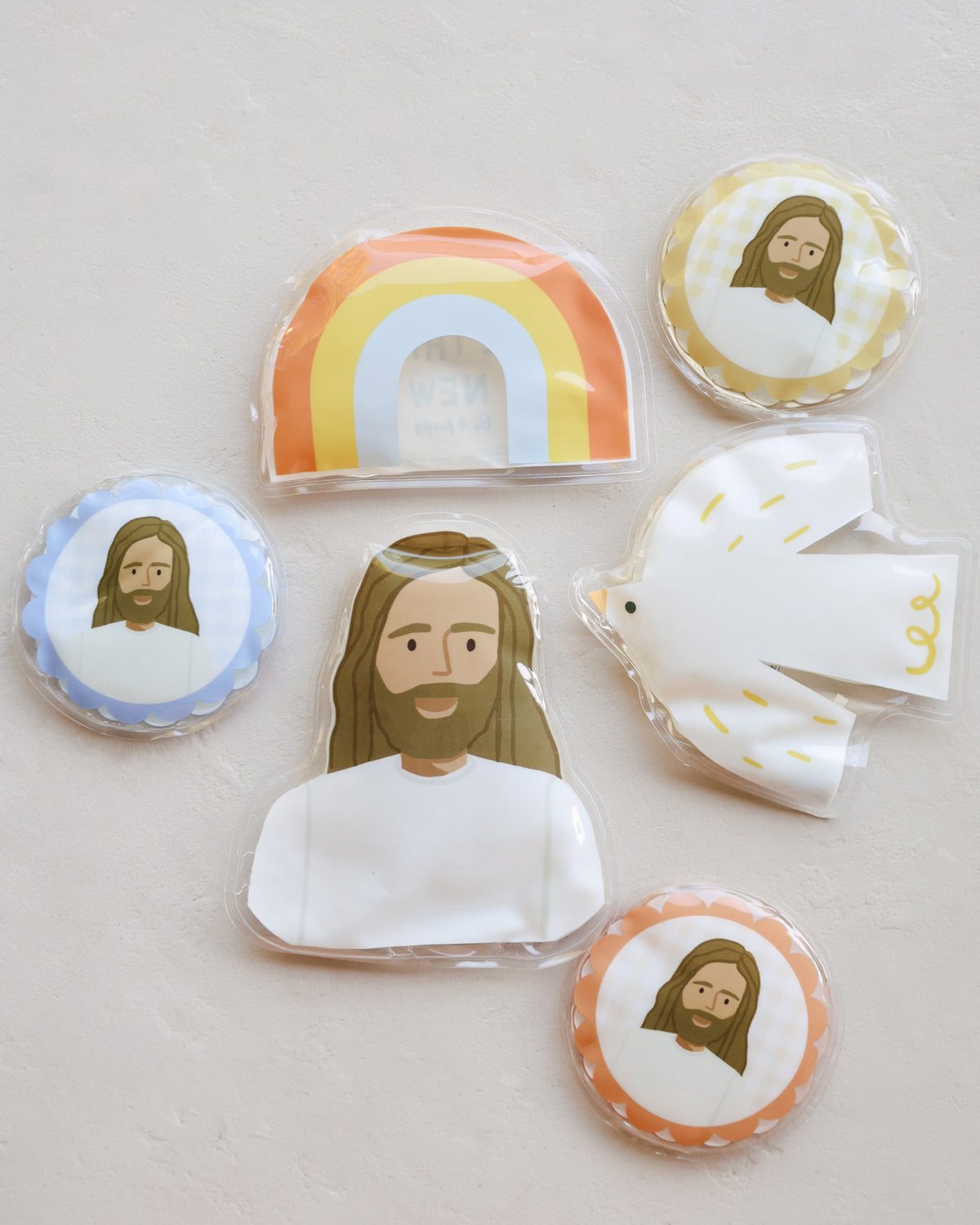 Flat lay of Jesus Heals round ice packs with Trinity rainbow, dove and Jesus gel packs for kids