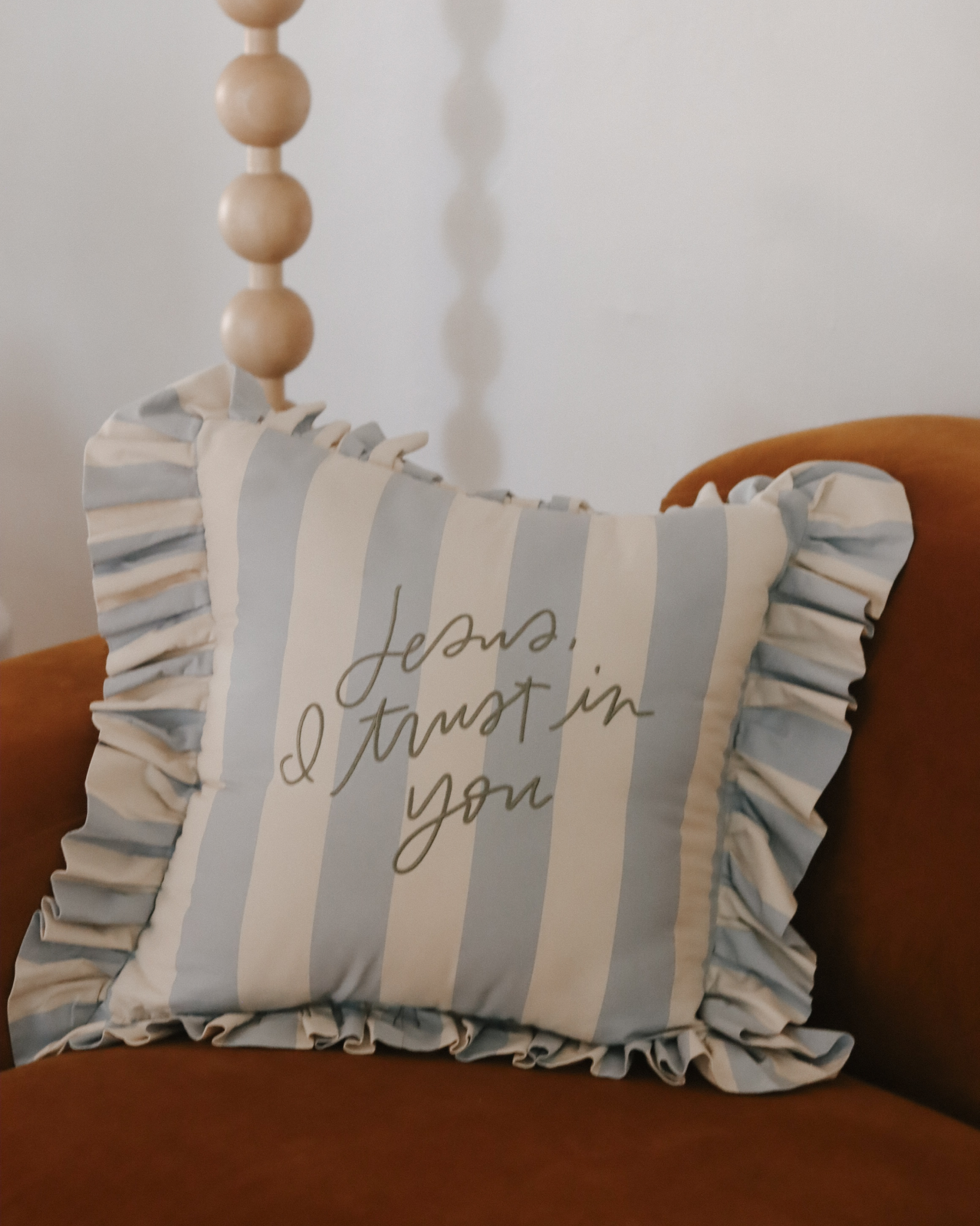 Light blue and cream striped ruffle pillow with sage embroidered ‘Jesus, I trust in You’ design, inspired by Divine Mercy devotion. Christian home décor accent pillow with cotton insert and 22-inch ruffled edge—perfect faith-based gift and prayer reminder for the home.
