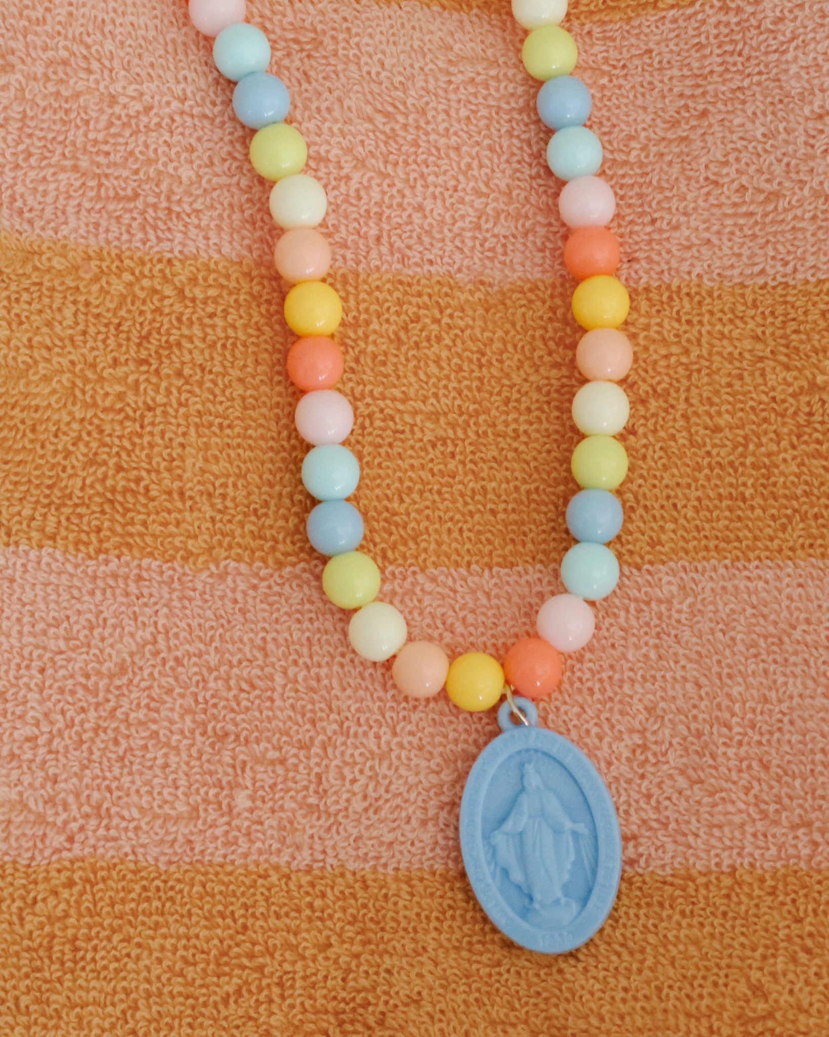 Children’s Miraculous Medal necklace with soft blue medal and colorful plastic beads on elastic strand. Christian kids’ jewelry for Marian devotion, First Communion, or faith-based gifts, reminding children of Mary’s protection and intercession.