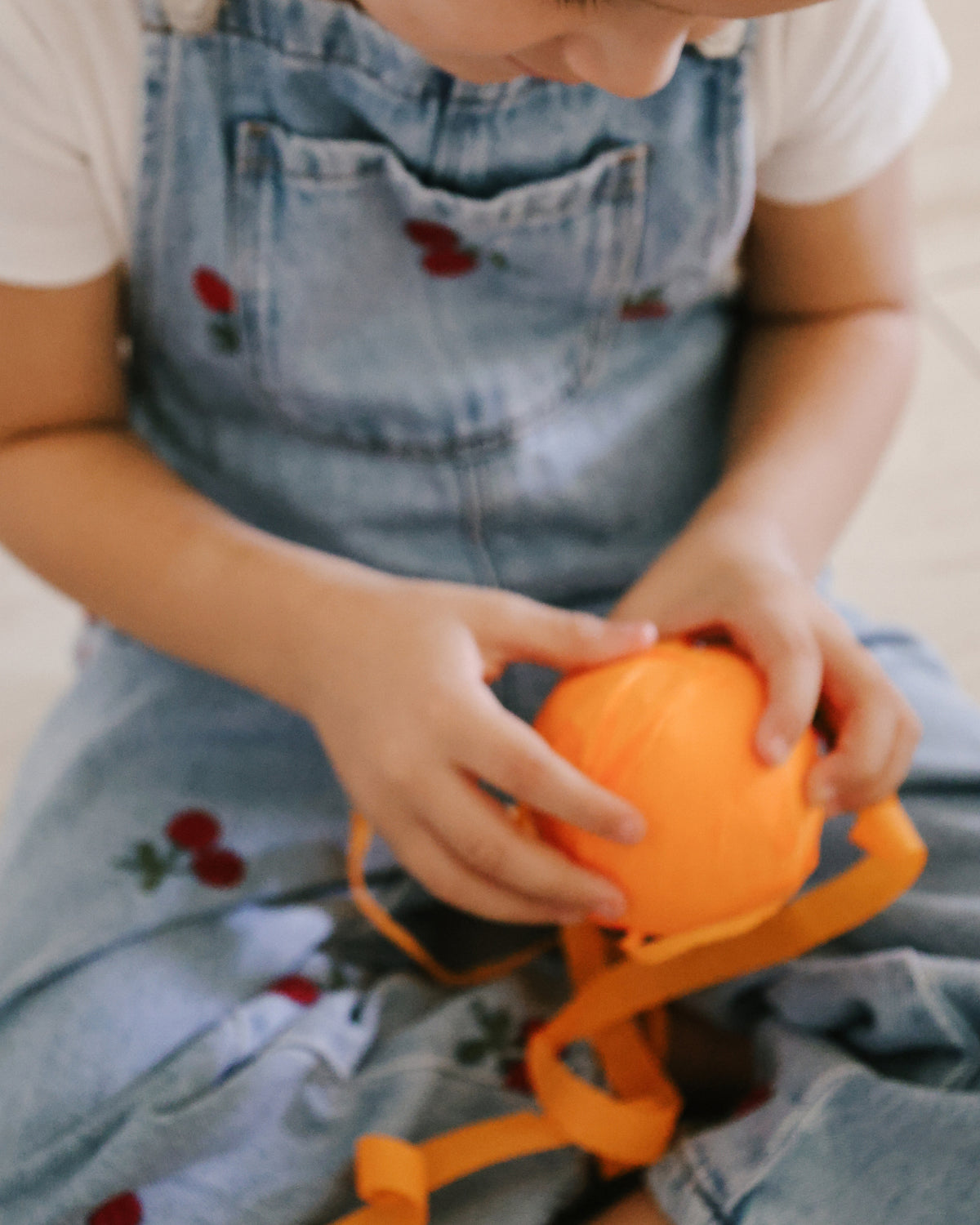 Child unwinding orange crepe paper from a St. Nicholas surprise ball