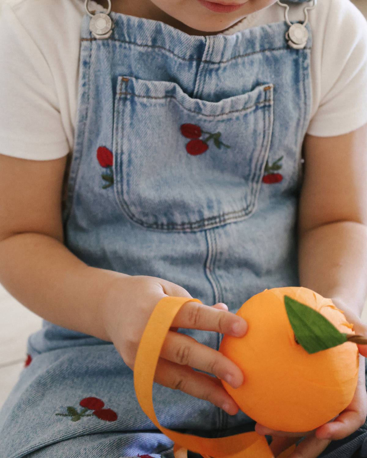 Close up of a child's hands unwrapping the St. Nicholas Orange Surprise Ball