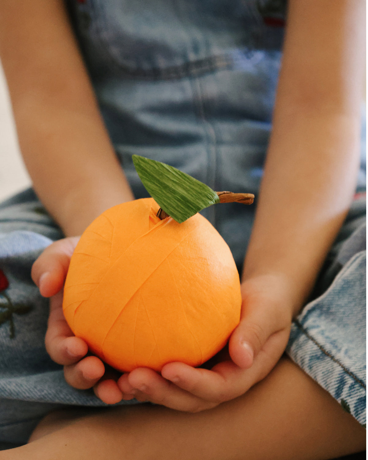 Child holding a St. Nicholas Orange Surprise Ball, a Catholic Advent tradition for December 6th