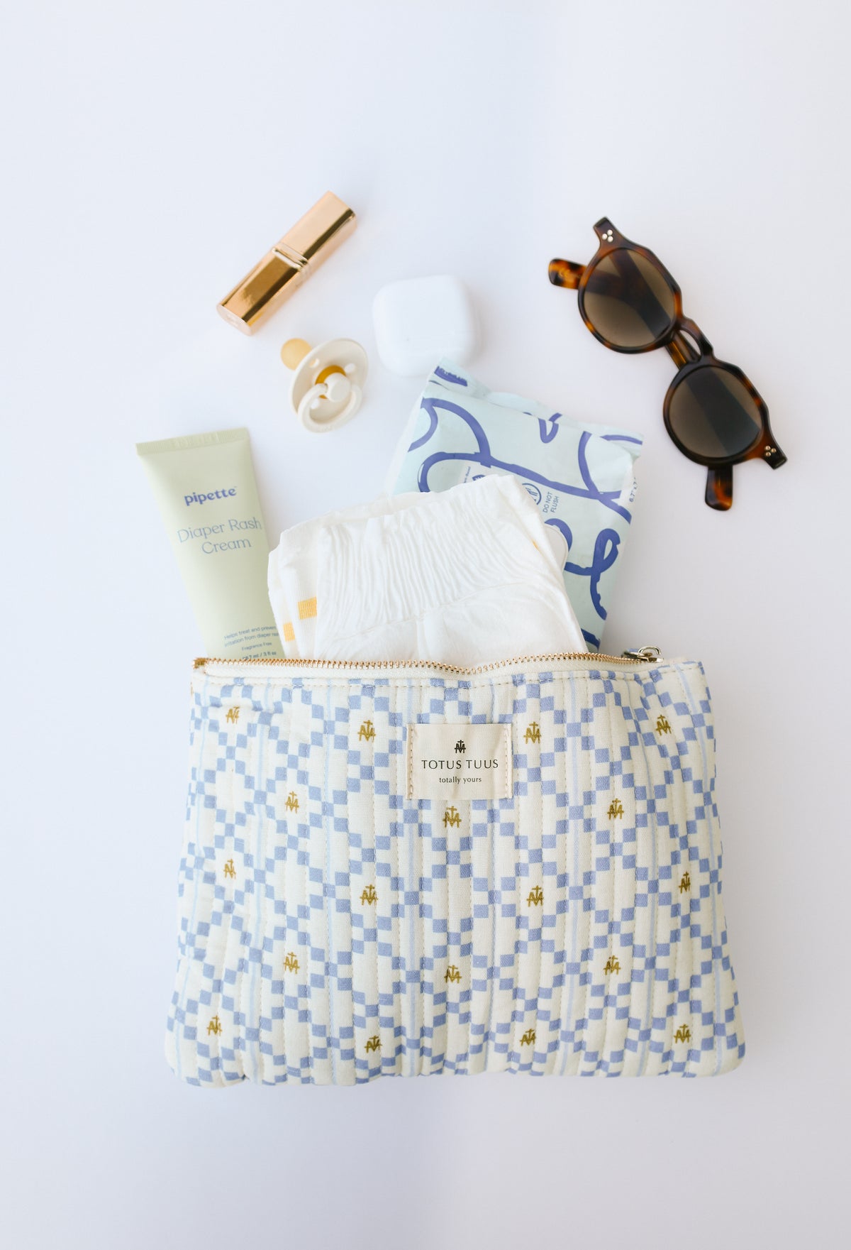 Marian quilted zipper pouch holding a diaper, lotion and lipstick, with sunglasses, a Catholic gift for new moms