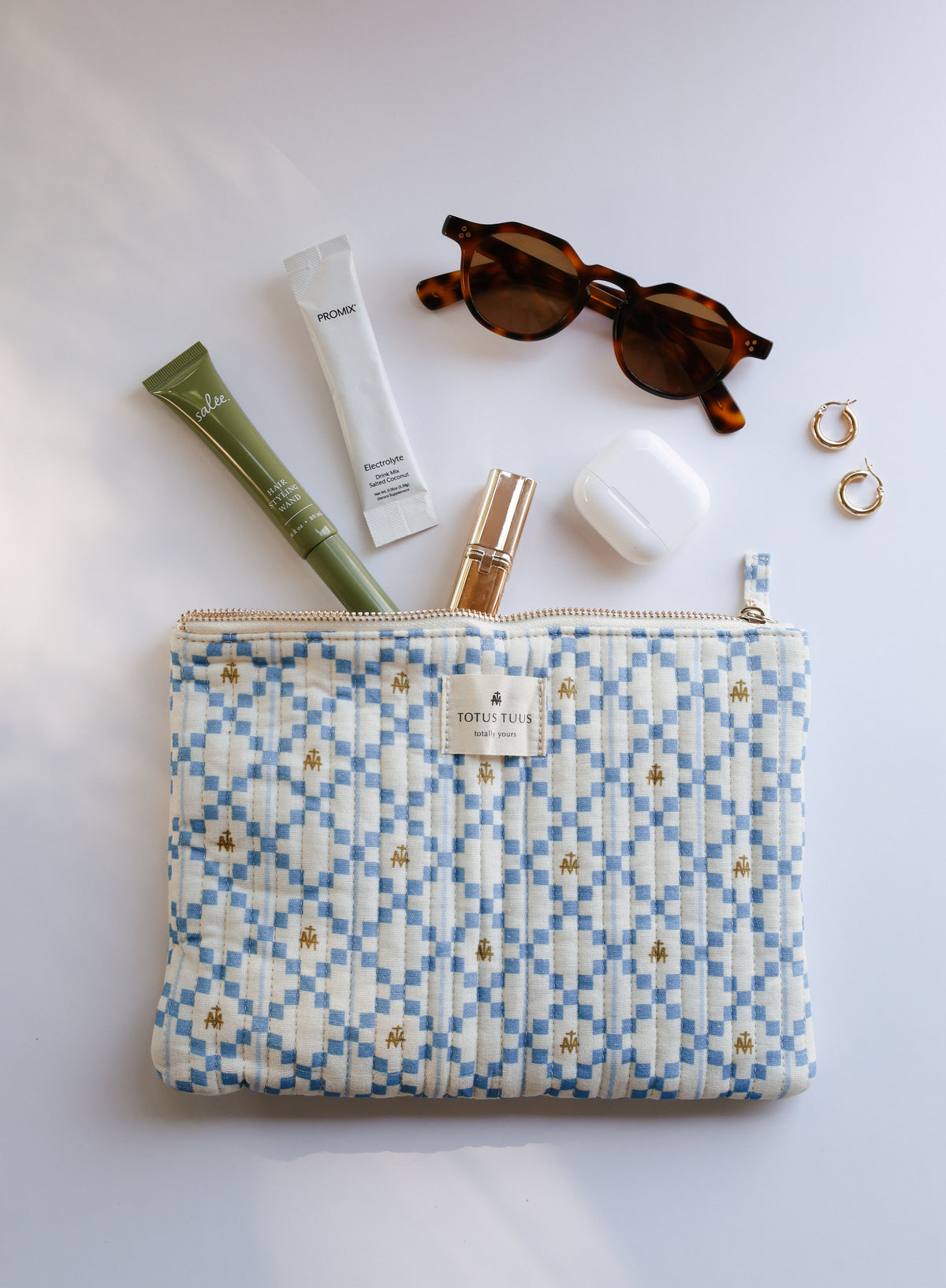 Blue and cream Marian quilted zip pouch with lip gloss, hand cream, earbuds and sunglasses