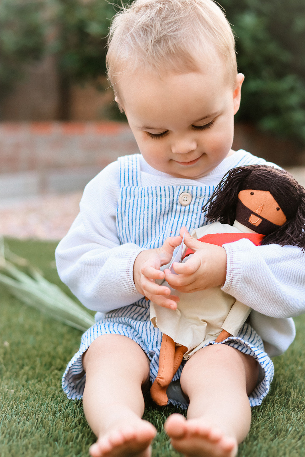 alt="A Toddler holding Jesus of Nazareth Doll"